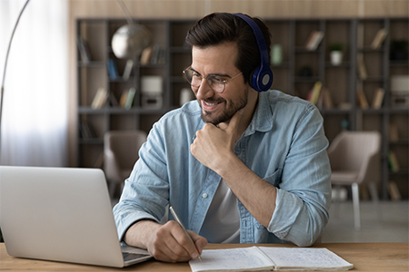 man in glasses in from of computer taking private language classes on line